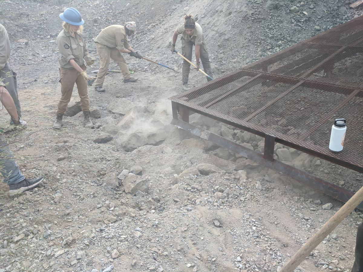 workers fill in a hole next to a metal structure