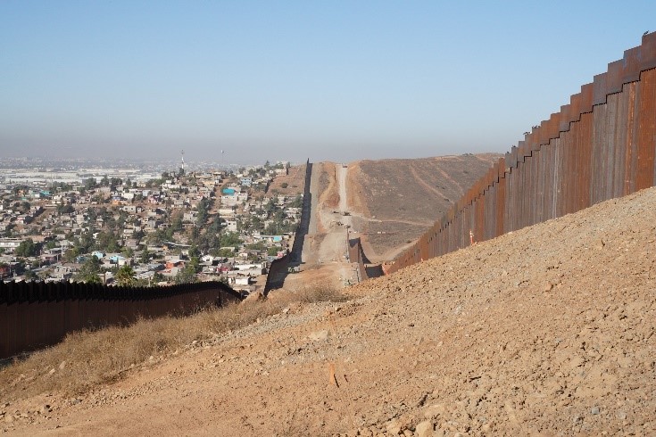 A dirt road next to the border wall.