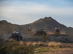 Three Off road vehicles follow a dusty trail towards a desert mountain. Photo by Kyle Sullivan/BLM.