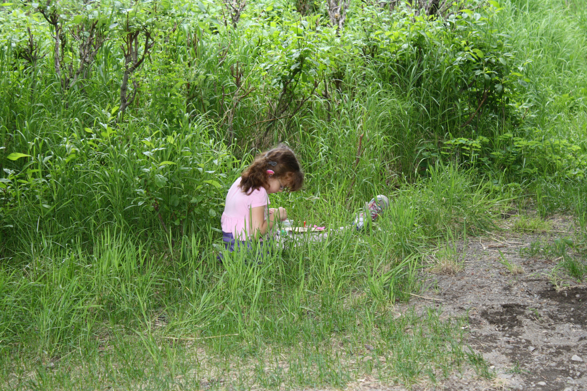 girl stting in the grass looking at leaves