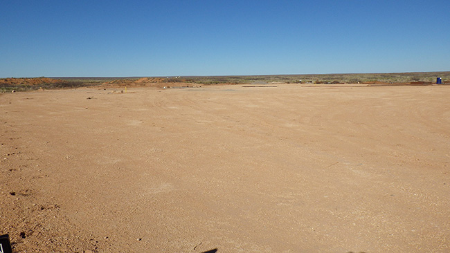 A well pad preceding reclamation showing a surface of bare dirt. BLM photo.