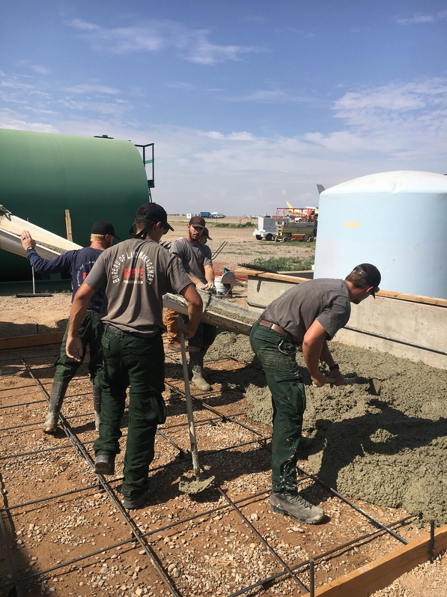 Pecos District fire crew members pour concrete slab to convert retardant from liquid concentrate to powder. 