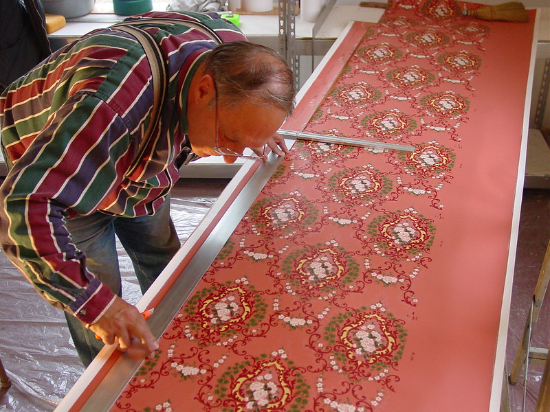 man measuring and cutting wallpaper