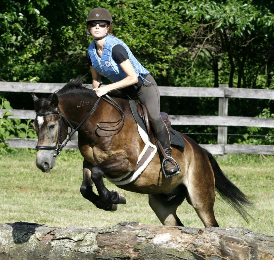 A woman on a horse jumping. 