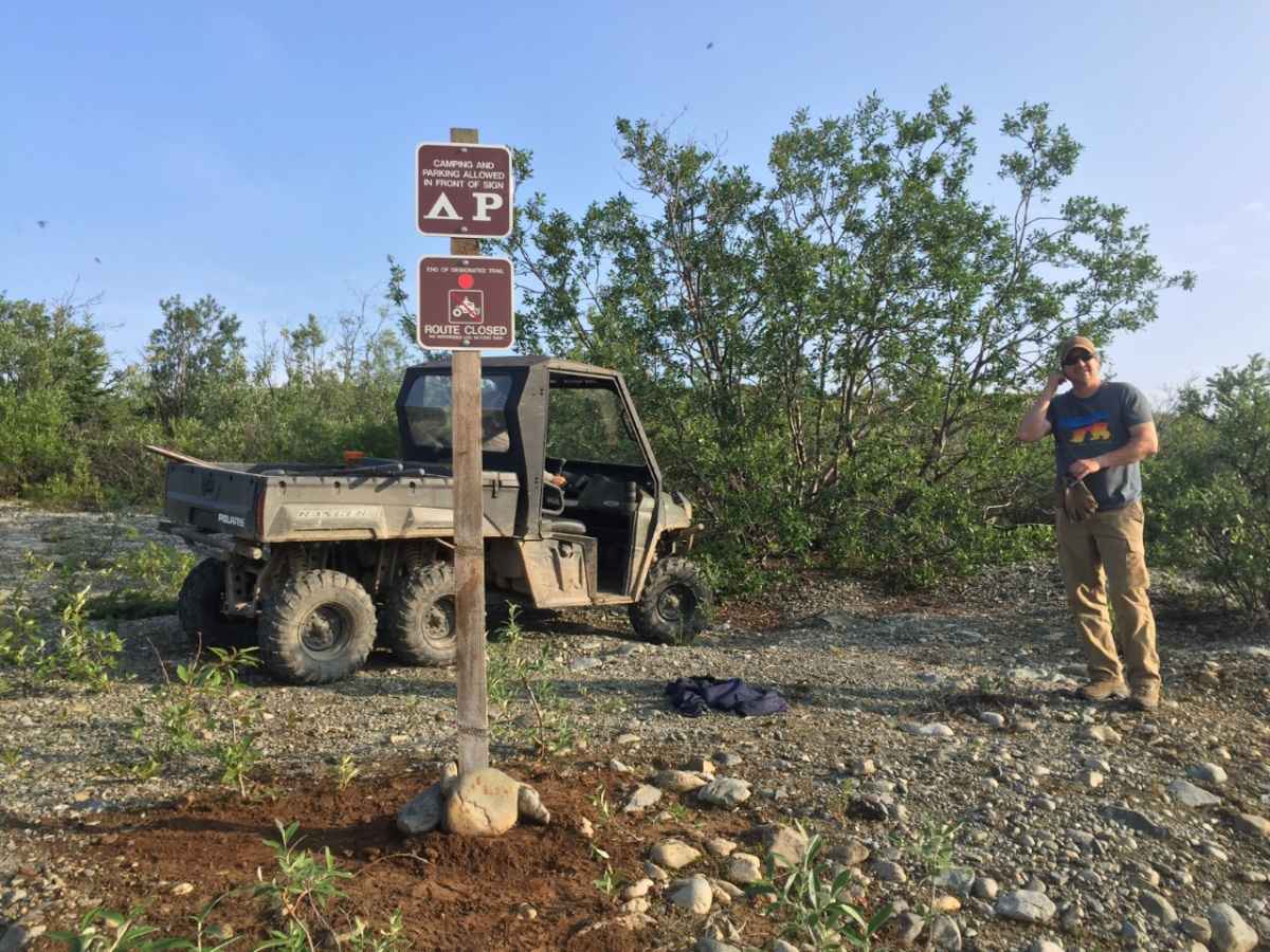 Man standing behind sign post