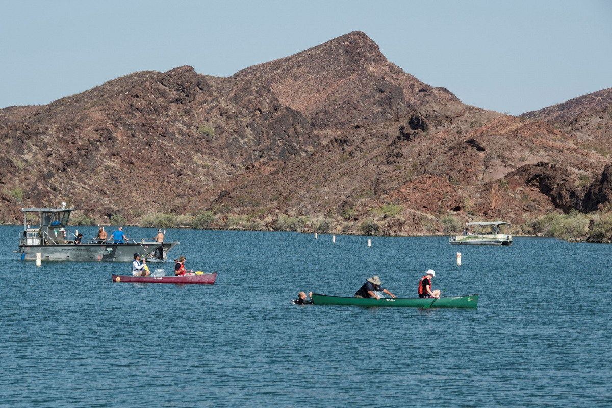 two canoes on a lake with larger boats in the distance