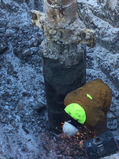 A worker cuts a well casing on an abandoned well near Point Simpson in the National Petroleum Reserve in Alaska.