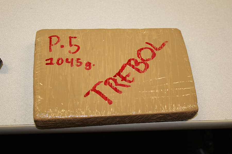 An brown, plastic wrapped rectangular cube of the narcotics marked with "P-5 1045g. TREBOL" in red ink