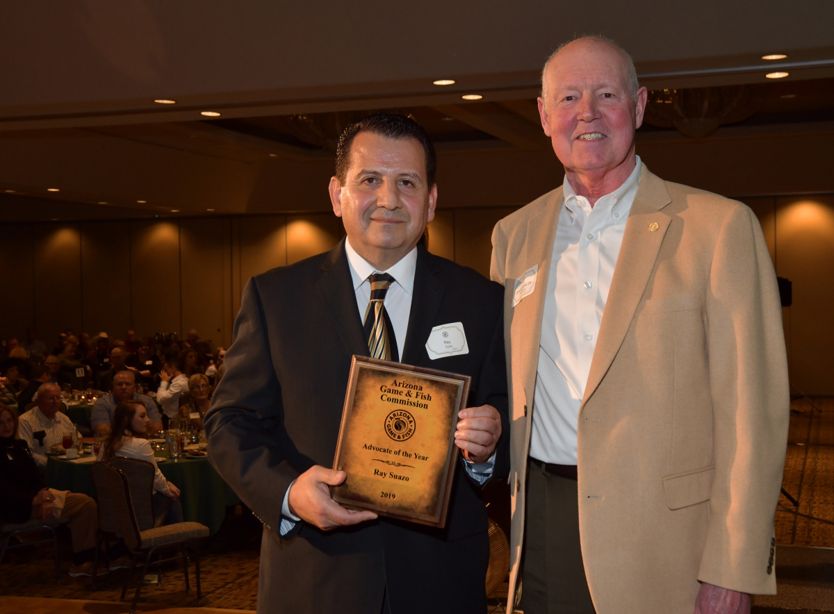 two men stand together. one holds a plaque