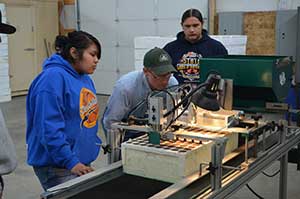 Shoshone-Paiute students learn how to operate the seeder alongside a US Forest Service Lucky Peak employee. The large-scale germination process used at the greenhouses has been modernized thanks to a vacuum needle seeder purchased through the cooperative agreement. The seeder ensures more accurate seed germination, increases the likelihood that more seedlings will be produced and wastes less seed than traditional manual seeding.