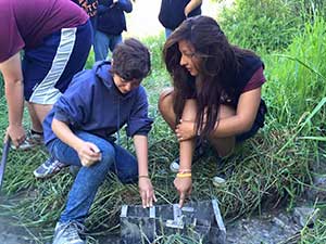 A Nature High Summer Camp hydrology intern shows a camper how to collect data.