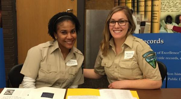 Two women at a table that features information about the BLM.