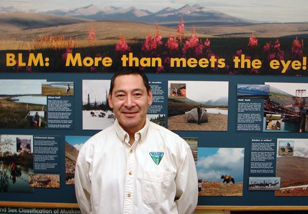 Brian standing in front of a display featuring information about BLM Alaska.