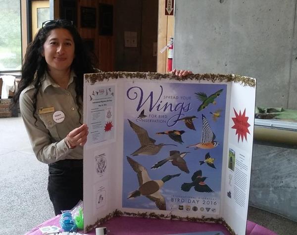 Denisse Escobar with a tri-fold display offering information about birds.