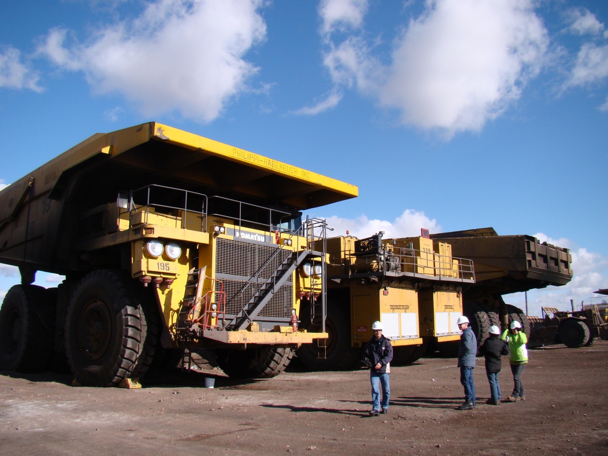 Four people standing in front of coal machinery.