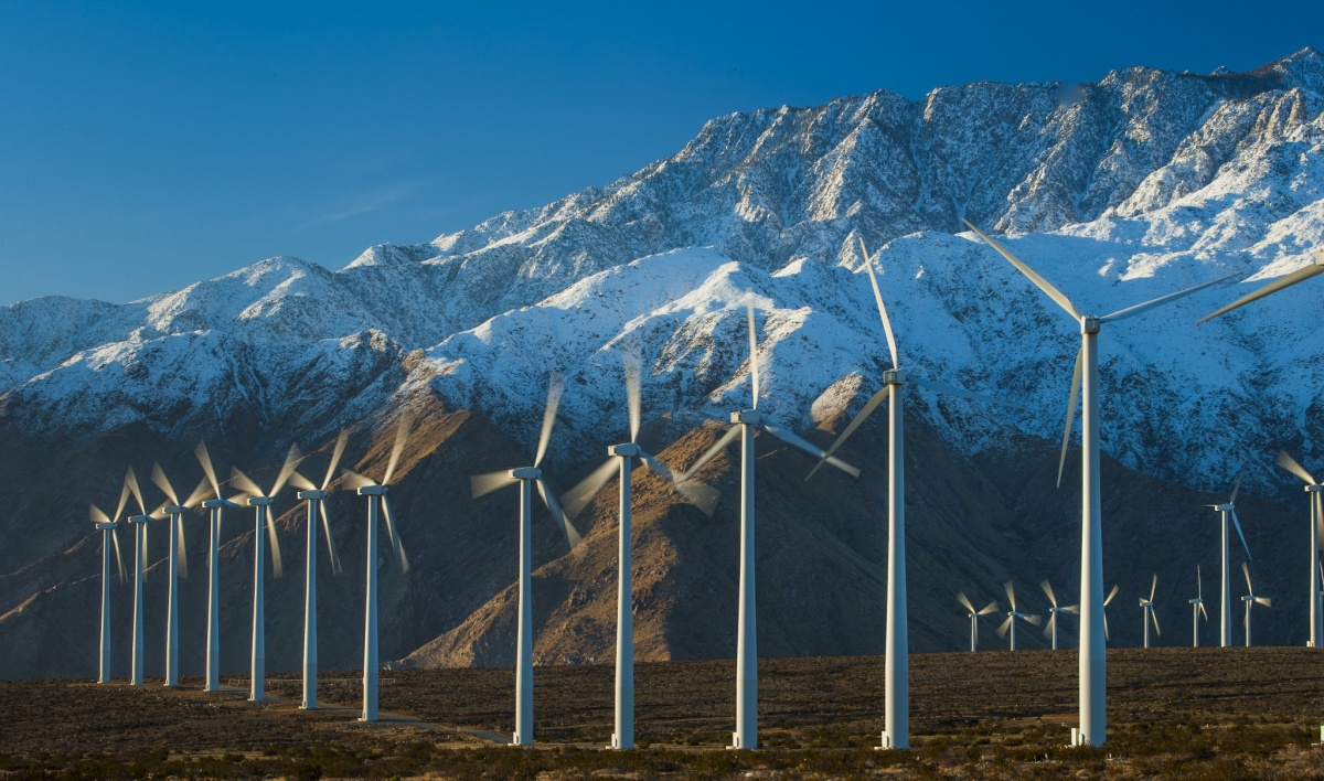 Wild turbines in the California desert with a mountain backdrop. Photo by Tom Brewster photography.