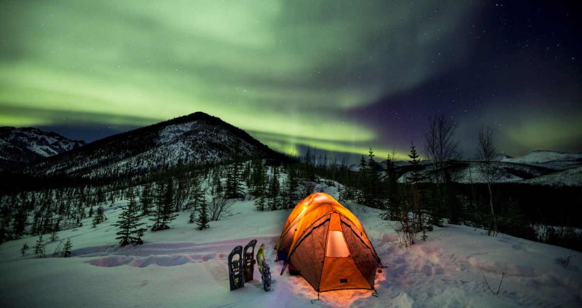 The northern lights over a glowing tent in the White Mountains of Alaska. Photo by Bob Wick, BLM.