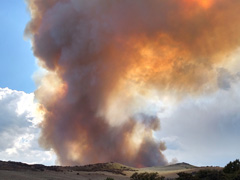 The sun shines orange through a rising plume of smoke. BLM photo.