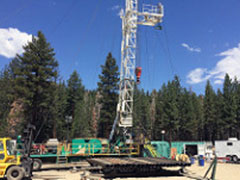 Machines, trucks, pipes and other heavy equipment in an open area near a forested area. Photo by Mark Spendel, BLM.