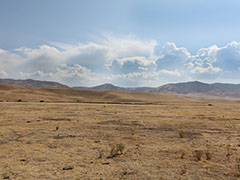 Storm clouds gather over a valley surrounded by hills. Photo by BLM.