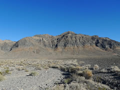 A dry valley with little vegetation sits near a rugged, dry, and barren mountain.  Photo by BLM. 
