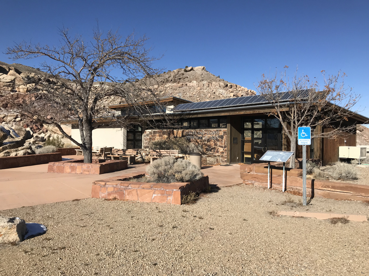 The Jurassic National Monument Visitor Center building in the fall with a leaf-less tree visible.