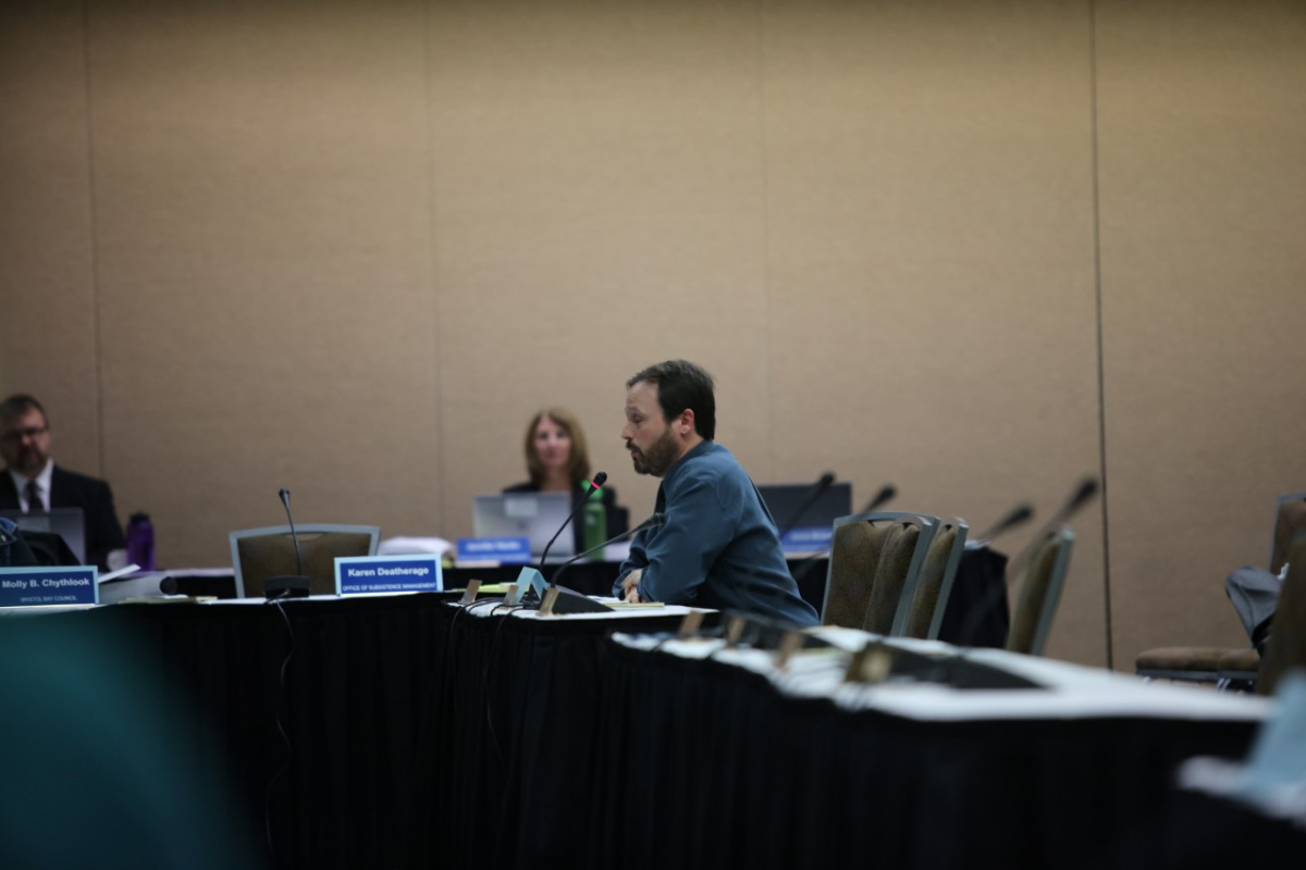 A man in a conference room talking into a microphone.