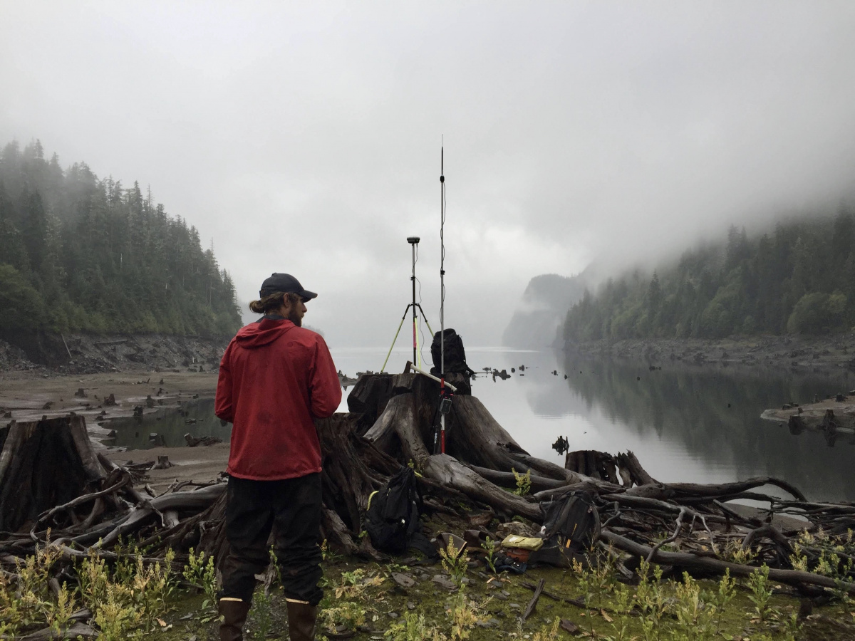 Man standing by GPS survey gear by water