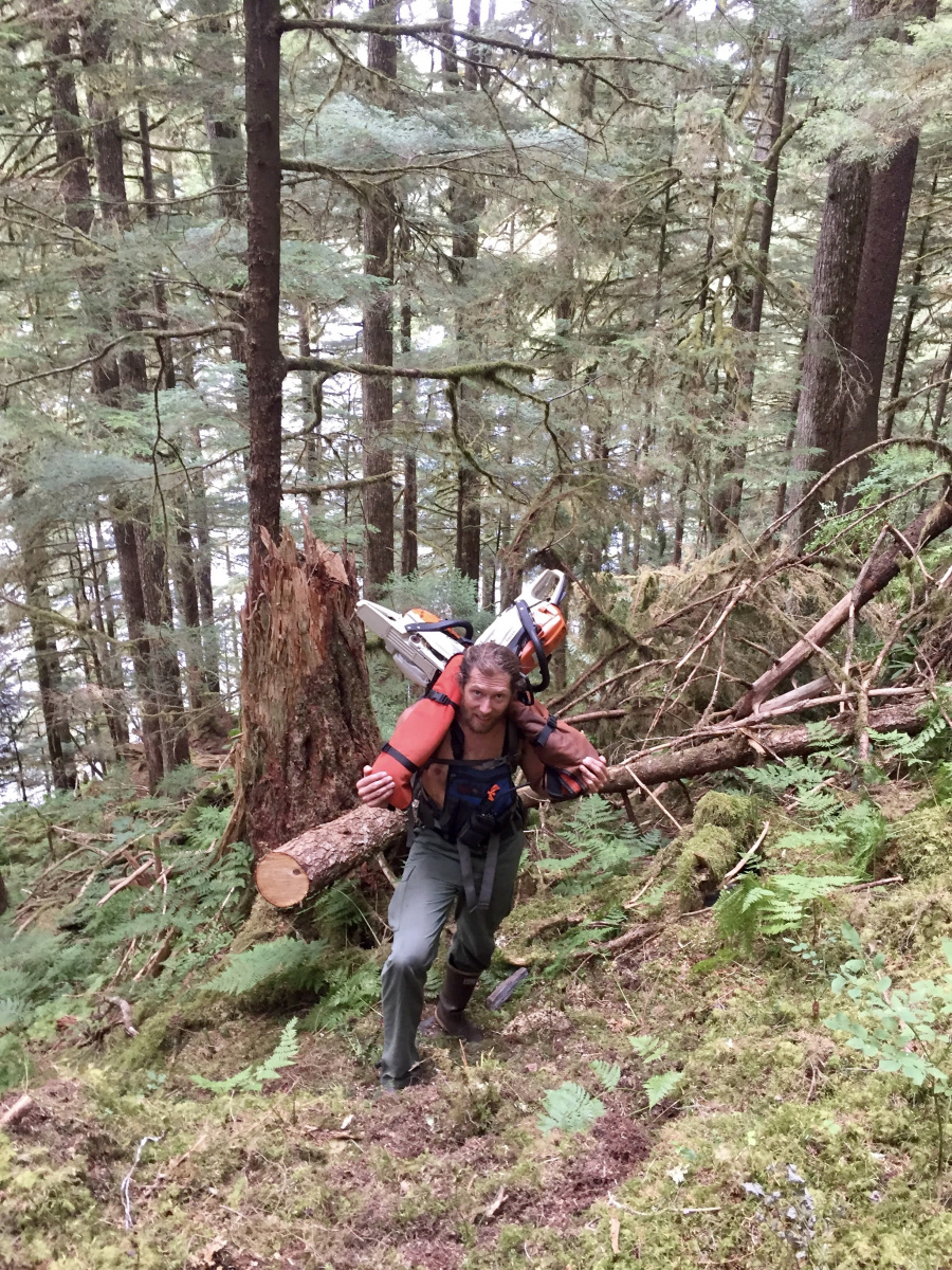 Man carrying chainsaws uphill