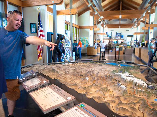 Interior of visitor's center with a man pointing at a scale model of the eastern Sierra Nevada. Photo by Jesse Pluim.