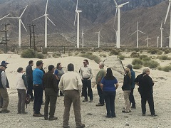 Attendees of the Desert Advisory Council Meeting stand in front of a field of wind turbines. Photo  by Sarah Webster/BLM.