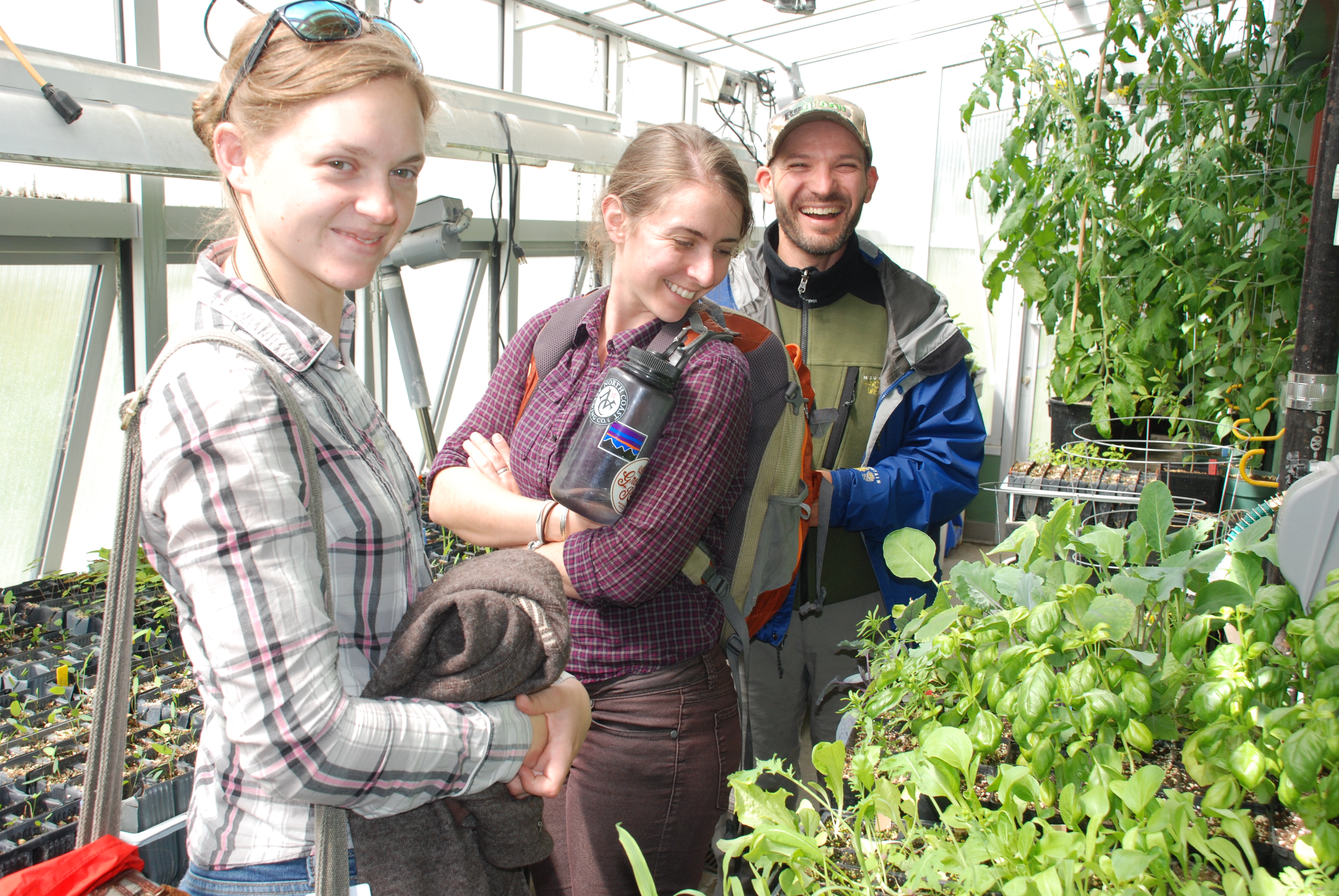 Seeds of Success interns Charlotte Crowder and Bonnie Bernard with seed program manager Lyubomir Mahlev smiling in the Plant Materials Center green house.