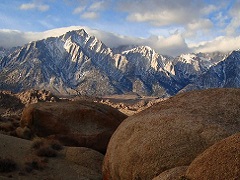 Round tan boulders with tall, snow capped mountains in the background. Photo by David Kirk./BLM.