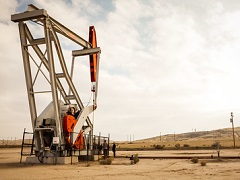 An oil derrick amidst dry, rolling hills. Photo by Jesse Pluim/BLM.