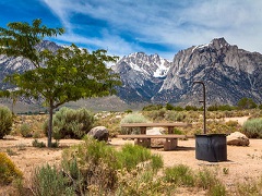 Campground with fire pit and picnic table. Towering Sierra Nevada Mountains in background. Photo by Jesse Pluim, BLM.