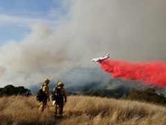 A tanker drops red fire retardant on a smoky hill. Photo by Rex Hambly, BLM.