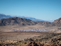 Elevated view of thousands of white RVs in a desert valley surrounded by steep mountains. Photo courtesy of Phil Henderson.. 