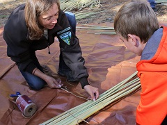 BLM Archaeologist Jennifer Rovanpera shows an Archaeology Day participant the beginning steps of creating a mat from tule reeds. Photo by Jeff Fontana, BLM