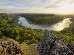 A river running through a landscape of mountains and forests.