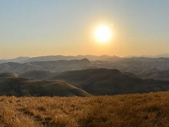 The sun sets behind layers of dry, rolling grasslands. Photo by John Ciccarelli/BLM.