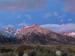 Image of snow capped mountains at the edge of a high desert at sunset. Photo by Miriam Morrill/BLM.