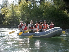 Image of family rafting down a swift river through a green forest. Photo by Bob Wick/BLM.