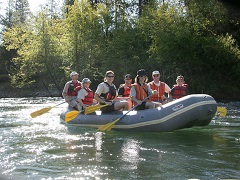 Image of family rafting down a swift river through a green forest. Photo by Bob Wick/BLM.