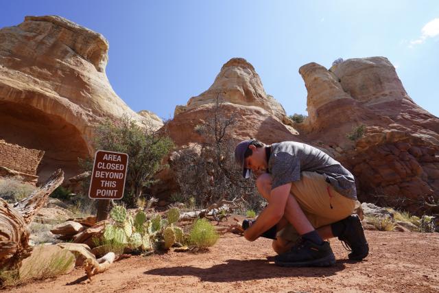 Man holds camera to sign in red rock area