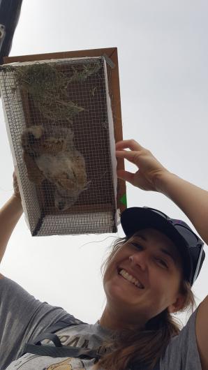 Lindsey Rush smiles as she holds up a pygmy rabbit in a box