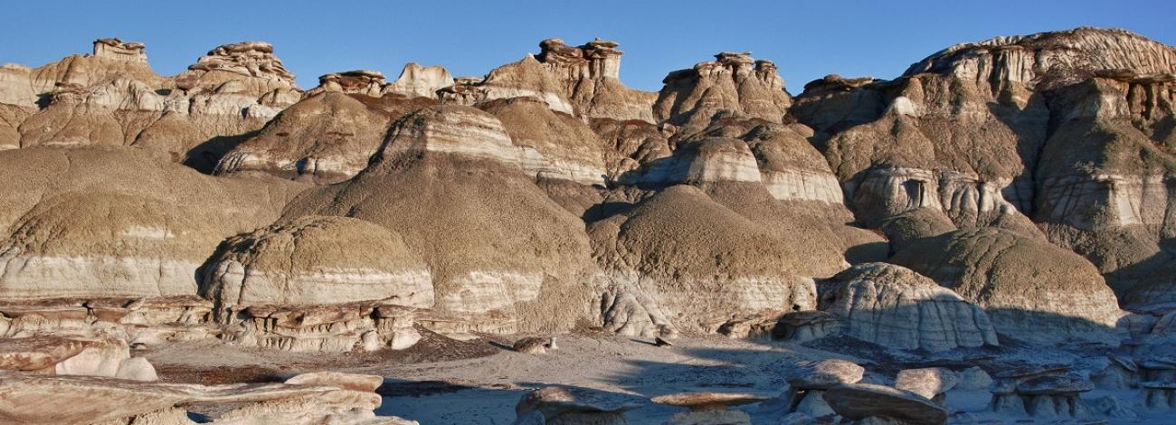 The landscape of sandstone cap rocks and scenic olive-colored hills with an interesting array of hoodoos and other formations in Ah-Shi-Sle-Pah Wilderness in New Mexico.
