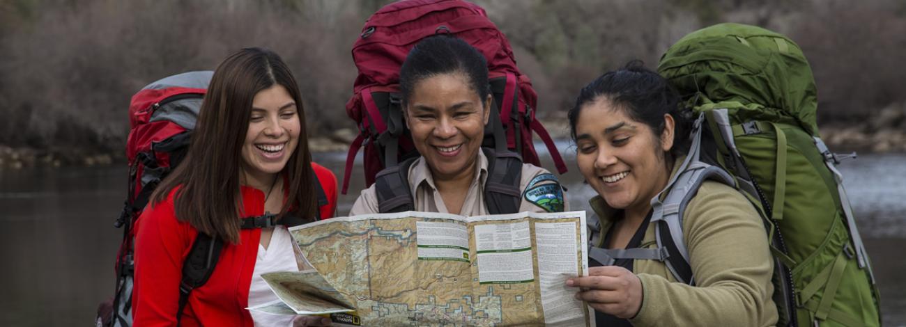 Three female backpackers looking at a map