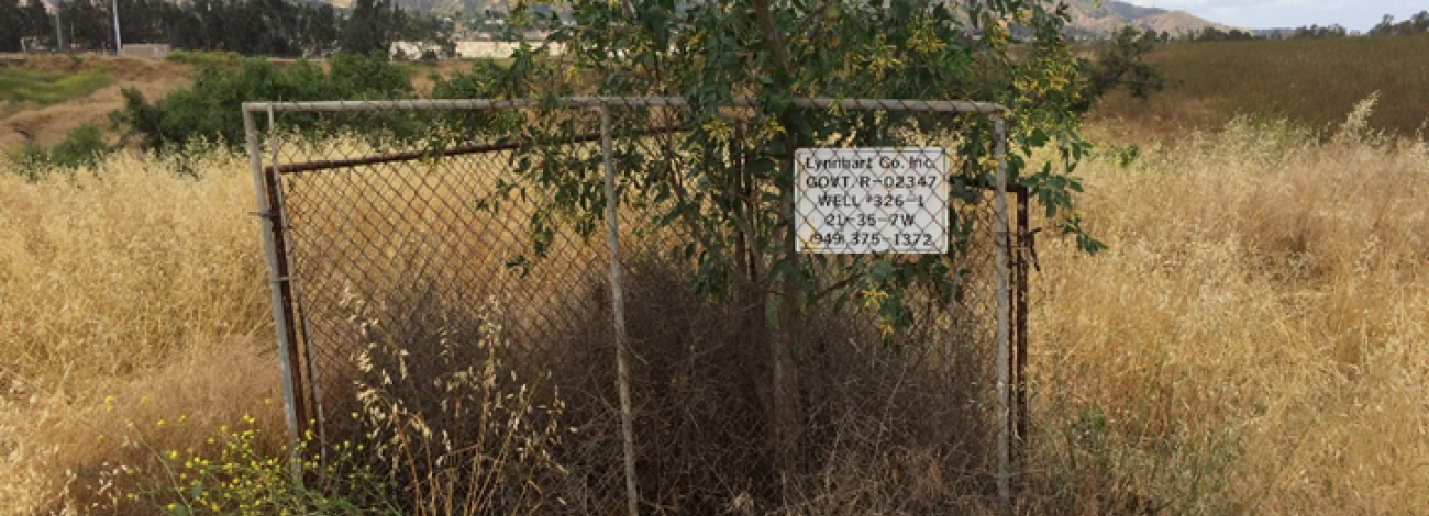an abandoned well site with vegetation growing through it