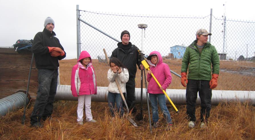 BLM Alaska surveyors buddled up standing with kids in Chevak, Alaska