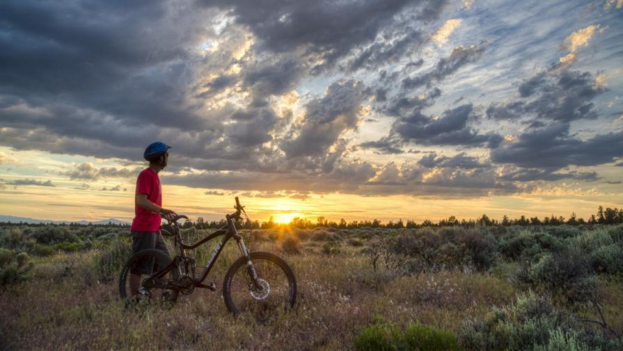 A man with his bike watches the sun behind the clouds at Cline Butte, Oregon. Photo by Bob Wick, BLM.